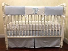 a white crib with blue trim and monogrammed bedding