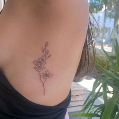 the back of a woman's shoulder with a flower tattoo on her left side