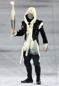 a man dressed in black and white is holding a light up rocket while standing on the ice