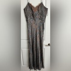 a dress hanging on a door handle in front of a white door with a black and brown paisley pattern