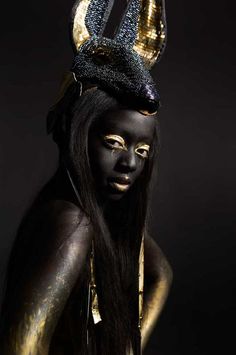 a woman in black and gold with horns on her head