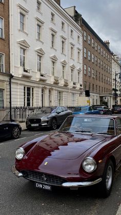 an old red car is parked on the side of the road in front of some buildings