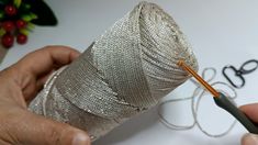 two hands are working on a piece of silver wire that is being sewn together