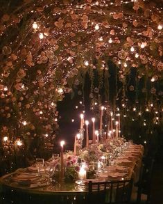 a long table with many candles and flowers on it is set for a formal dinner