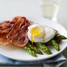 a white plate topped with asparagus and bacon next to a glass of milk