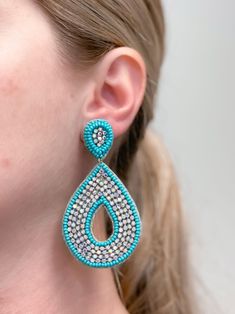 a close up of a person wearing some kind of blue and white earring on their ear