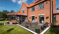 a large brick house with patio furniture and potted plants on the front lawn area