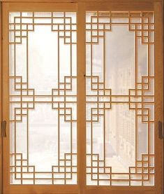 an open window with wooden frame and decorative design on the glass door, in front of a cityscape