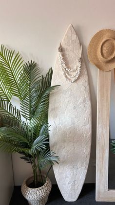 a white surfboard next to a mirror and potted plant