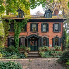 an old brick house with green shutters and ivy growing on the roof, surrounded by greenery