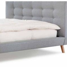 an upholstered bed with white linens and pillows on the headboard, against a white background