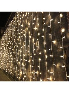 a wall covered in white lights next to a building