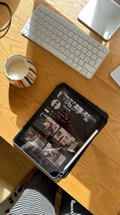 an ipad sitting on top of a wooden desk next to a keyboard and mouse,