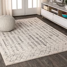 a large rug in the middle of a living room with a white chair and window behind it