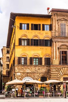 an old building with tables and umbrellas outside