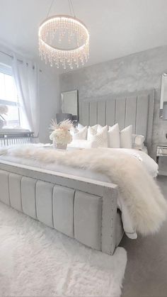 a bed with white fur on the headboard and foot board in front of a window