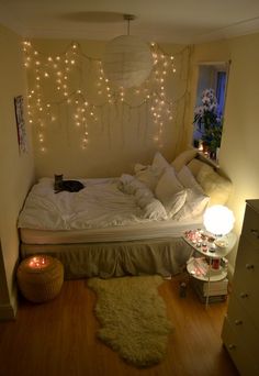 a bedroom with lights hanging from the ceiling and a bed in front of a window