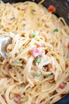 a fork in a bowl filled with pasta and vegetables