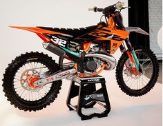 an orange and black dirt bike sitting on top of a stand