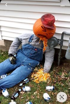 a person sitting on the ground with beer cans around him and an orange pumpkin hat over their head