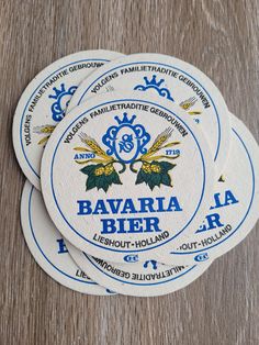 three white coasters with blue and yellow designs on them sitting on a wooden surface