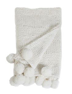 a white knitted blanket with pom poms on the bottom and one side