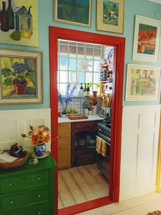 a kitchen with pictures on the wall and an open door to another room in it