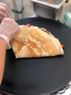 a pancake is being prepared on a grill with a gloved hand in the foreground