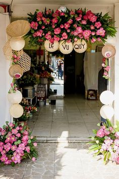 the entrance to a flower shop with flowers hanging from it's ceiling and decorations on either side