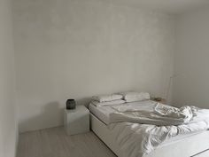 an unmade bed sitting in a bedroom next to a white wall and flooring