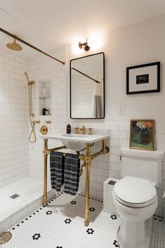 a bathroom with black and white flooring and gold fixtures on the wall, along with a mirror above the toilet