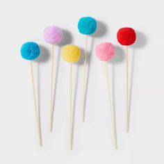 four different colored pom - poms sitting on top of each other in front of a white background