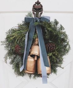 a wreath with bells and pine cones hanging on the front door to give it a festive touch