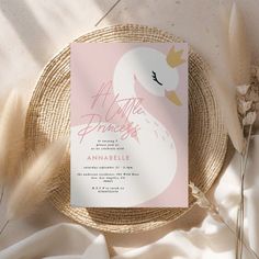 a pink and white wedding card on top of a plate next to some dried flowers