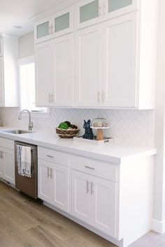 a kitchen with white cabinets and stainless steel dishwasher on the counter top in front of an oven