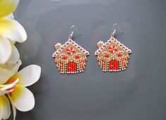 a pair of beaded earrings sitting on top of a table next to a flower