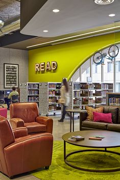 a library with couches, chairs and tables in front of a sign reading read