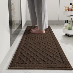 a person standing on top of a brown rug in a kitchen next to a counter