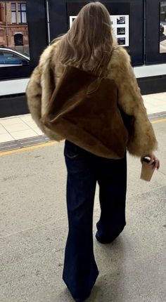 a woman is walking down the street with her coat on