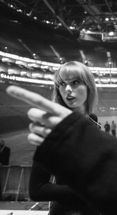 black and white photo of two people pointing at something in front of the camera on an empty stadium