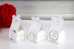 three small bags with white balls in them on a table next to a red rose