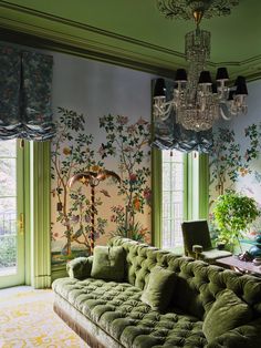 a living room with green couches and chandelier