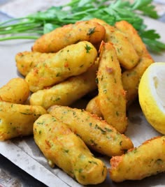 some fried food on a plate with lemon and parsley