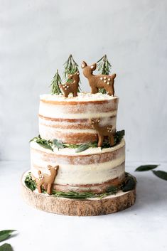 a three tiered cake decorated with deer figurines and pine trees on top