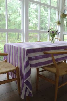 the table is covered with a purple and white striped cloth next to two wooden chairs