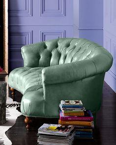 a living room with a green leather chair next to a coffee table filled with books