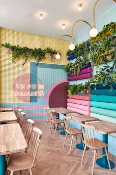 a colorfully decorated restaurant with lots of plants on the wall and wooden tables in front of them