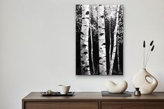 a black and white painting on the wall above a dresser with two vases next to it