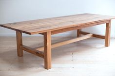 a large wooden table sitting on top of a hard wood floored floor next to a white wall