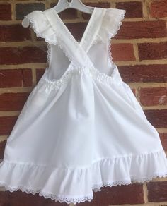 "We used this over a long sleeved red dress(not included).This is a beautiful white pinafore Swiss dot made in USA-in the 80s-no issues/smoke free environment-labeled sz 6- waist elasticized back 11\"-12\"/length (top to bottom) 21 1/2\"/petit lace trim on ruffle sleeve caps and bottom ruffle-no issues(37)" White Ruffled Suspender Dress For Spring, White Sundress Suspender Dress With Ruffles, Fitted White Suspender Dress With Ruffles, Cotton Prairie Dress With Ruffles For Garden Party, Cute White Suspender Dress With Ruffles, Cotton Smock Dress For Picnic, White Lace Trim Dress For Picnic, Cotton Lace Trim Dress For Picnic, White Swiss Dot Cotton Dress